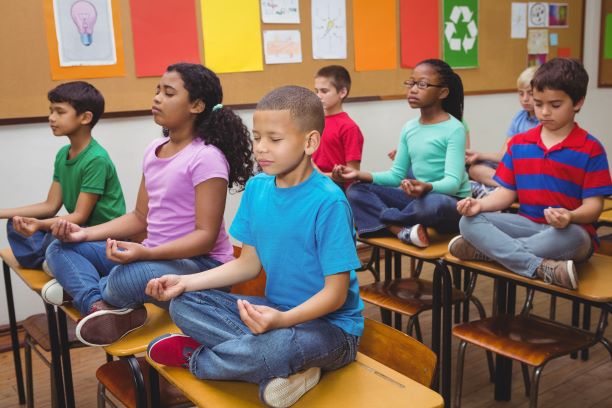 Elementary school students meditating in classroom
